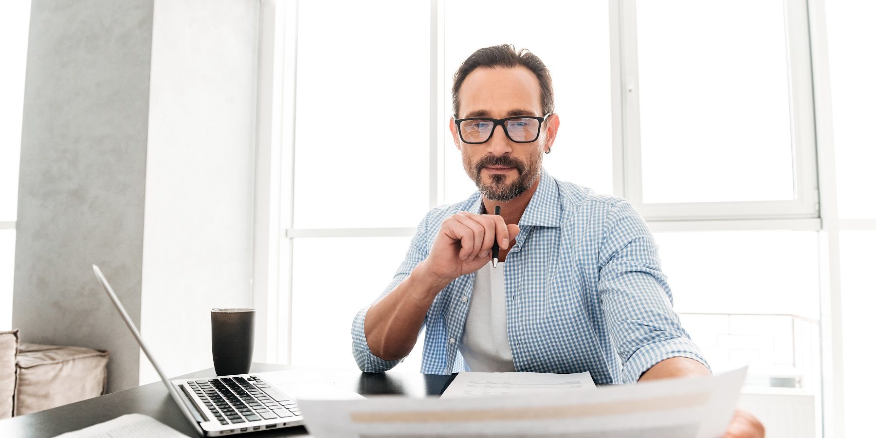 Immagine di persona che guarda soddisfatta dei documenti e ha il computer portatile alla sua destra