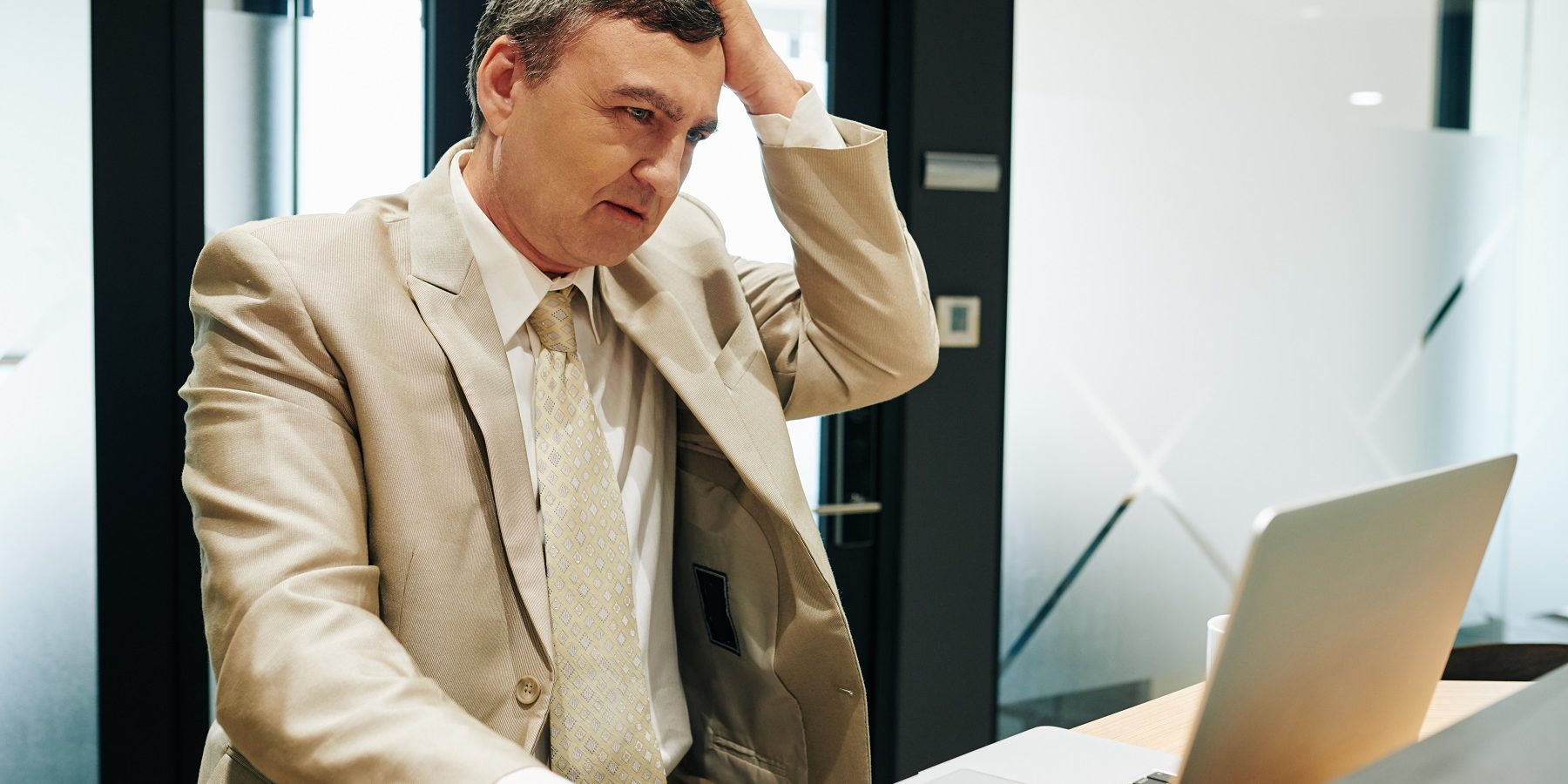 Manager ha problemi con la connessione internet Immagine di una persona che guarda lo schermo del suo computer portatile e si porta una mano alla testa in segno di grattacapo da risolvere