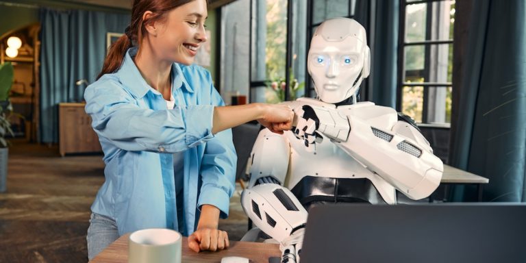 Immagine di giovane donna che batte un cinque con il pugno chiuso a un robot